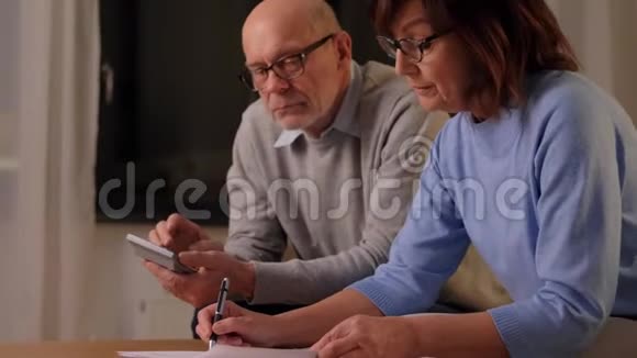 家里有纸和计算器的老夫妇视频的预览图