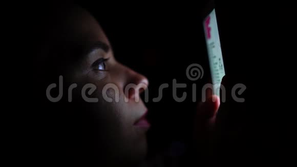 在黑暗中使用手机的成年女性带智能手机的年轻女性在家中卧室视频的预览图