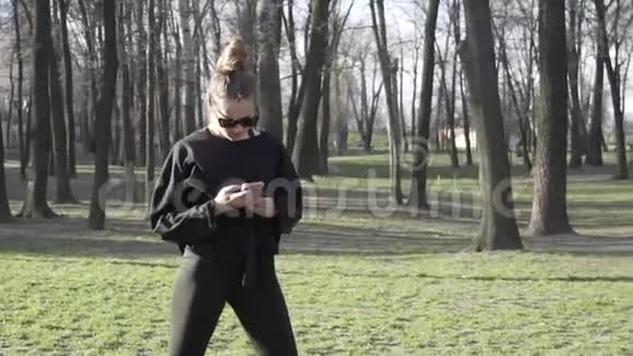 年轻女性在公园健身训练前锻炼健康的年轻女性在户外热身被分散注意力视频的预览图