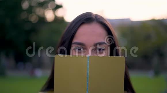 有趣的阿拉伯女孩神秘地用一本书遮住了她的脸4K视频的预览图