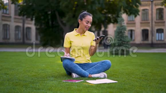 移动连接漂亮的拉丁女孩坐在公园里打电话穿蓝色牛仔裤和黄色的女人视频的预览图