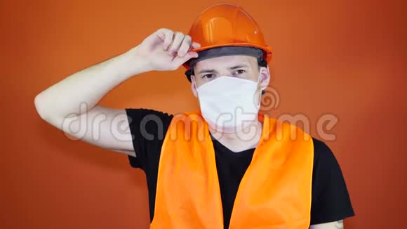 橙色背景下戴医用面具的年轻人的肖像成年男性用面罩覆盖面部视频的预览图