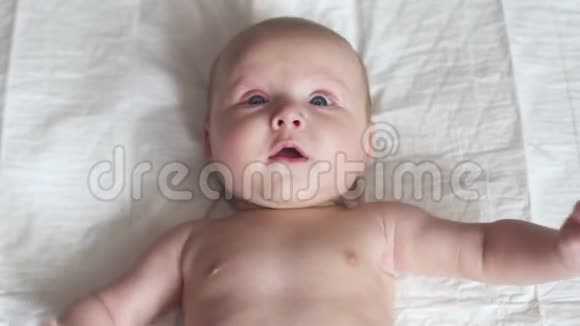 快乐的新生儿婴儿学步床上动动手微笑试着说话母性视频的预览图