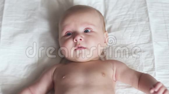 快乐的新生婴儿幼儿在床上移动双手微笑和尝试交谈视频的预览图