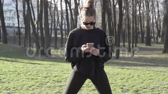 年轻迷人的女人在公园工作时使用手机健康的年轻女性在户外热身被分散注意力视频的预览图