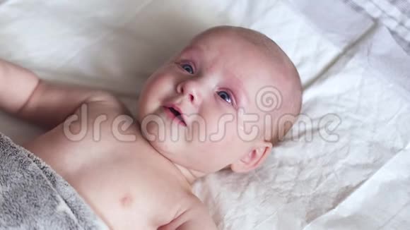 新生儿躺在床上的尿布上动动手微笑着试着说话视频的预览图