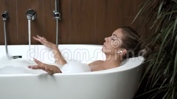 在家洗澡的女孩放松地听电话里的耳机音乐视频的预览图