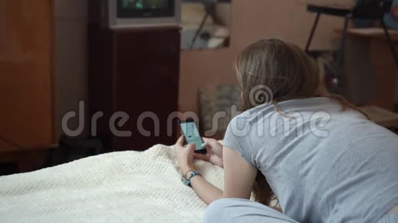 女孩躺在一个小房间的床上看着一台小电视视频的预览图