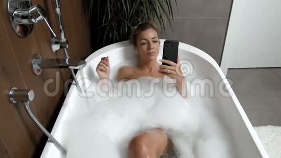 在家洗澡的女孩放松地听电话里的耳机音乐视频的预览图