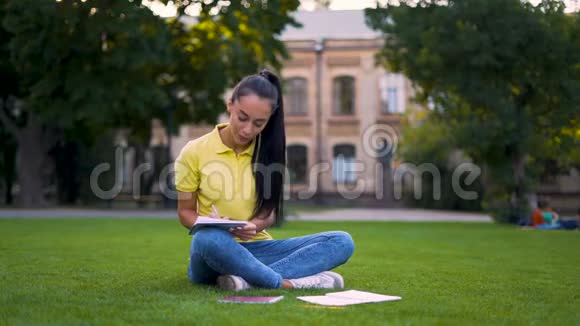 专注的女学生坐在公园里做作业4K视频的预览图