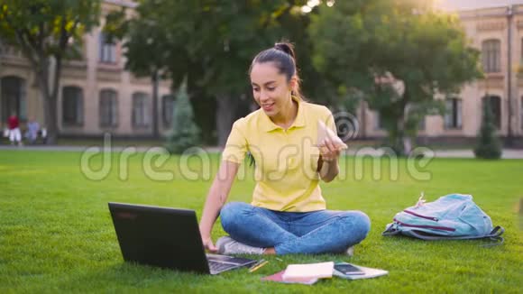 20岁的年轻女孩午餐时在电脑上工作女孩有一个三明治并发出一个信息4K视频的预览图