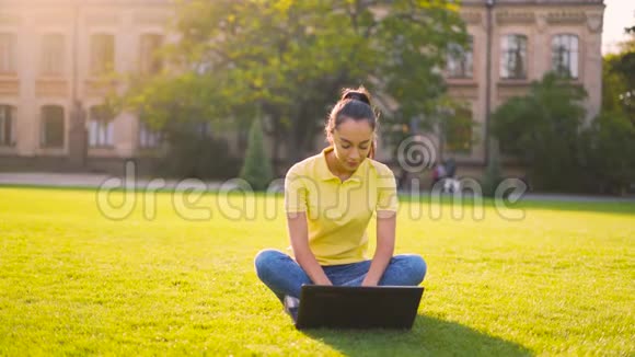 20岁的小女孩在公园的一台电脑上工作4k视频的预览图
