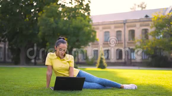 女孩坐在草坪上做网上购物视频的预览图