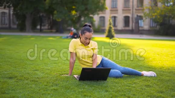 一个女孩坐在草坪上为博客写一篇文章4K视频的预览图