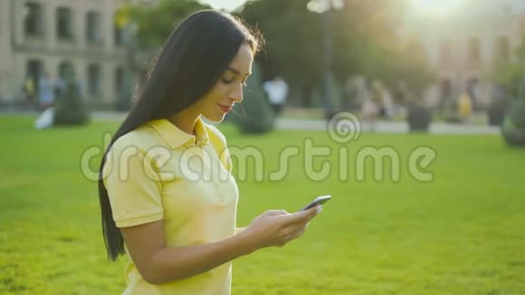 特写肖像女性手拿着智能手机拨一条信息公园外面的女人视频的预览图