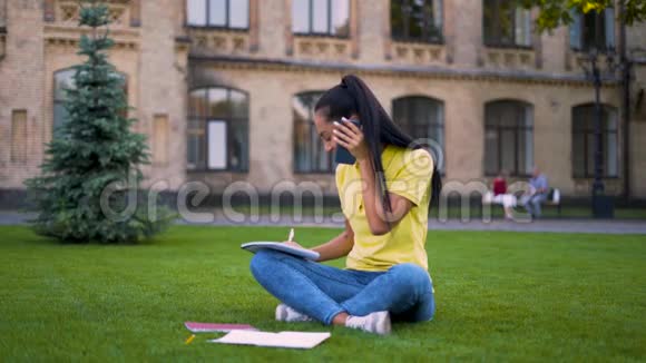 漂亮的拉丁女孩坐在公园里打电话穿蓝色牛仔裤和黄色T恤的女人视频的预览图