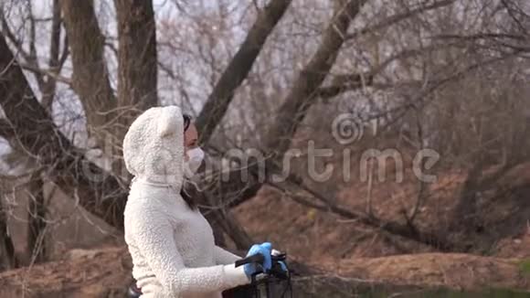 戴着医用口罩和手套的年轻女子骑着自行车站在农村手握舵保护妇女视频的预览图