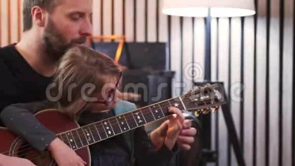 爸爸和女儿一起弹吉他小女孩在家和父亲一起学吉他前景吉他课视频的预览图