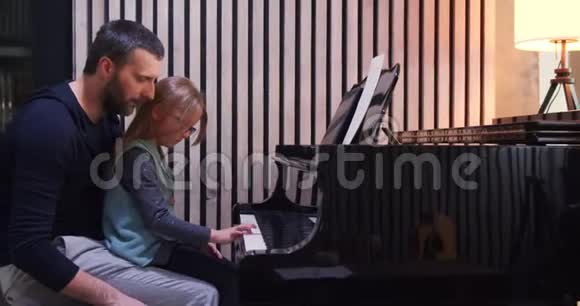 爸爸给女儿教钢琴小女孩在家学钢琴侧视家里的钢琴课儿童学习视频的预览图