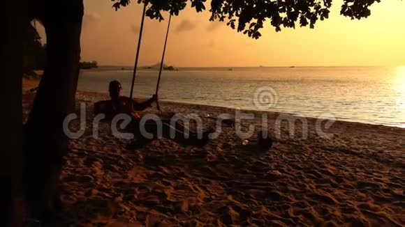 人坐在海边的木秋千上荡秋千视频的预览图
