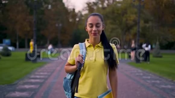 追踪摄像头穿黄色T恤的学生在公园里散步视频的预览图