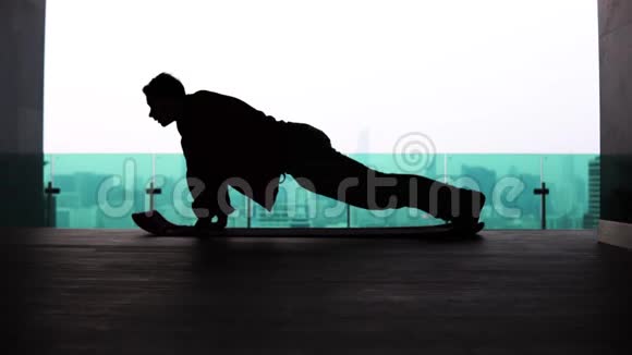 大都市背景下一个男人在楼顶做俯卧撑的剪影视频的预览图
