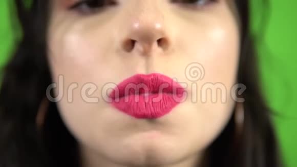 性感女孩在绿色屏幕上吹粉红色泡泡糖特写粉色口红视频的预览图