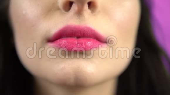 年轻女子把泡泡糖放在嘴里特写肖像粉唇视频的预览图