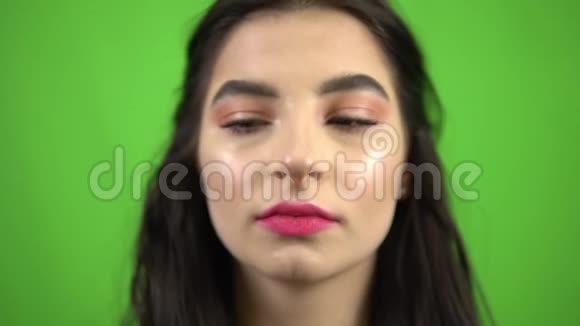 美女贪玩的女孩把粉红色的泡泡糖放进嘴里在绿色的屏幕上吃糖果视频的预览图