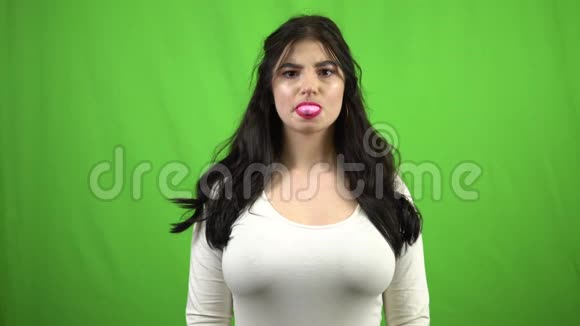 布鲁内特女孩在绿屏上吹泡泡糖视频的预览图