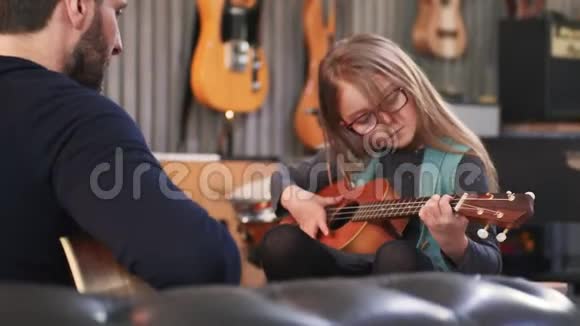 爸爸给女儿教吉他和四弦琴小女孩在家学吉他快关门在家上Ukulele课视频的预览图