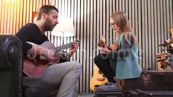 爸爸给女儿教吉他和四弦琴小女孩在家学吉他侧视在家上Ukulele课视频的预览图