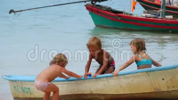 三个学龄前儿童正在海滩上玩耍视频的预览图