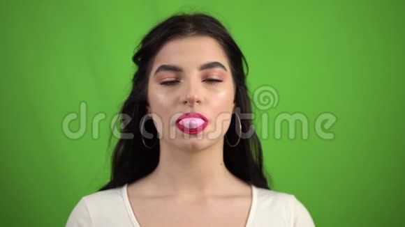 绿色屏幕上性感的黑发女孩吹着粉红色的泡泡糖视频的预览图