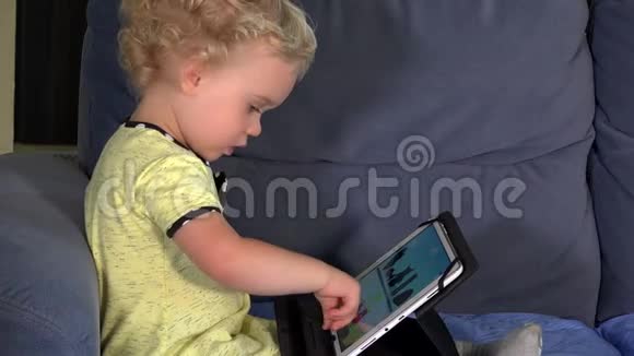 宝贝女孩玩使用智能媒体平板电脑坐在沙发上4K视频的预览图