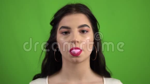 性感女孩吹泡泡糖口香糖在绿色屏幕上慢动作视频的预览图