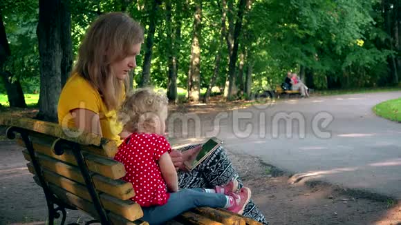 母亲和女孩用平板电脑坐在公园的长凳上现代教育4K视频的预览图
