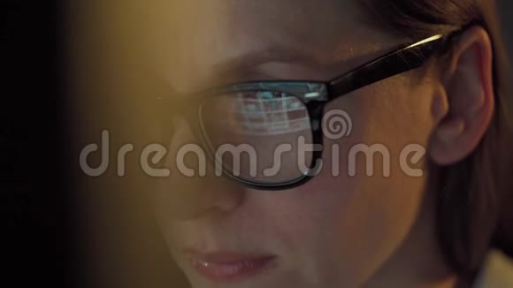 戴眼镜的女人看着显示器和上网监视器屏幕反映在眼镜上极端视频的预览图