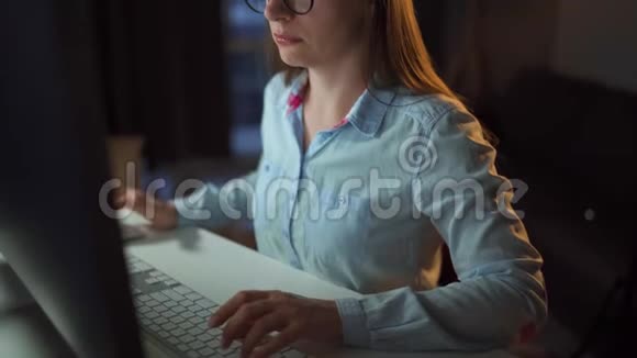 戴眼镜的女人看着显示器和上网监视器屏幕反映在眼镜上工作地点视频的预览图