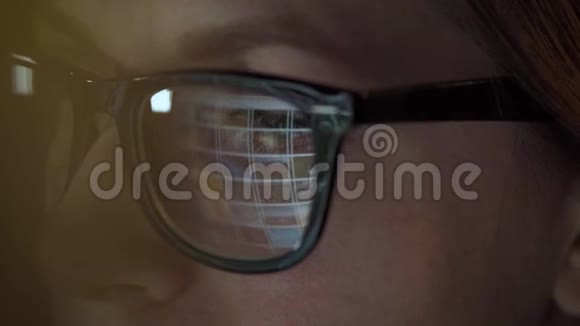 戴眼镜的女人看着显示器和上网监视器屏幕反映在眼镜上极端视频的预览图