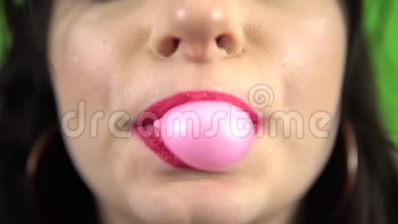 年轻女孩嚼着泡泡糖明亮的粉红色嘴唇合上绿色的屏幕视频的预览图