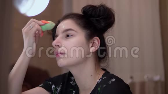 女孩用海绵在脸上混合粉底化妆视频的预览图