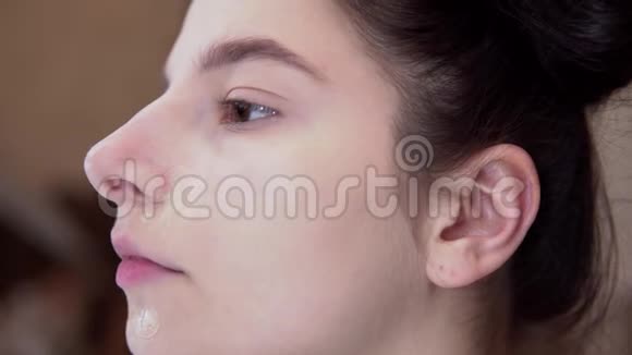 年轻女孩混合基础与海绵化妆视觉艺术家特写的脸视频的预览图