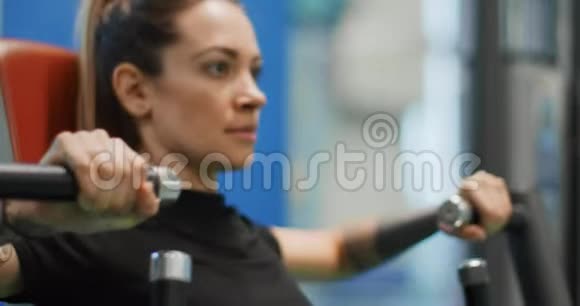 女性在胸部按压机上锻炼女子训练在健身房机器侧视特写慢动作女人压杠视频的预览图