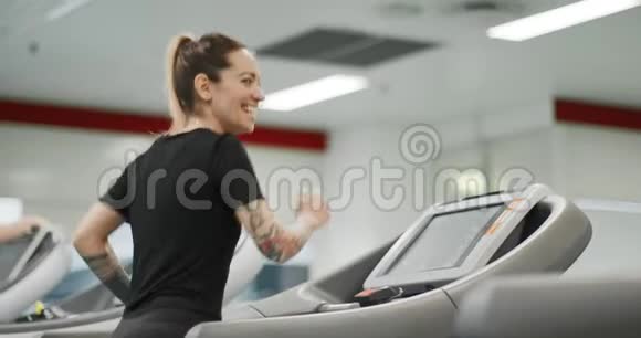 年轻女子在健身房跑步机上跑步后景健身中心女子训练女性锻炼有氧运动视频的预览图