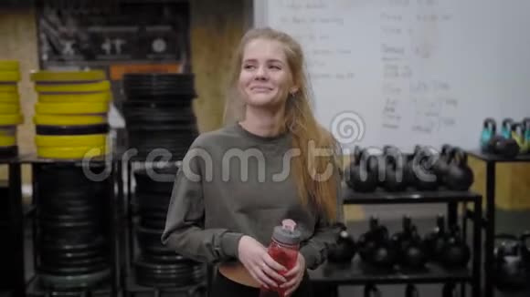 快乐的微笑女孩在训练前穿过体操馆拿着瓶子和水视频的预览图