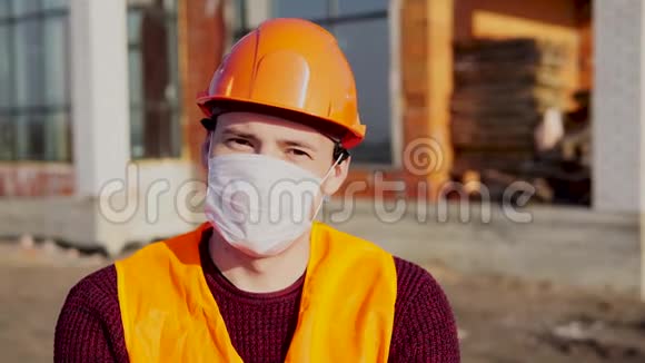 在建房屋背景上戴医用口罩工作服的男建筑工人画像视频的预览图