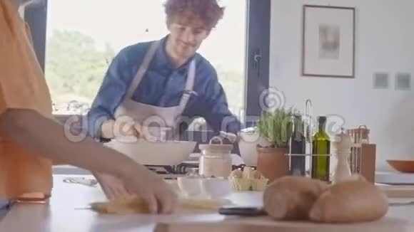男人在平底锅里煮和翻炒炒意面年轻人一起做饭和准备食物意大利面视频的预览图