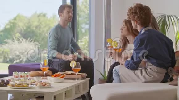 四个朋友开心交谈吃喝鸡尾酒快乐人群享受现代家庭聚会晚餐或午餐视频的预览图