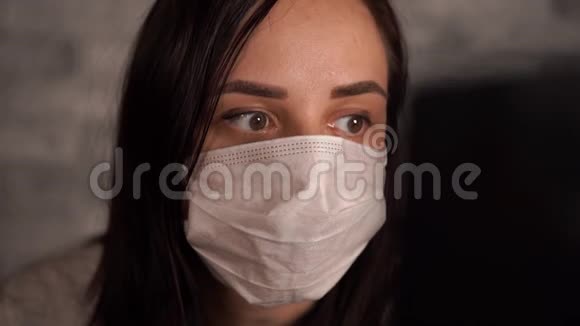 一个戴着医用面具的女人用笔记本电脑从互联网上得知冠状病毒的消息女性关心的是视频的预览图